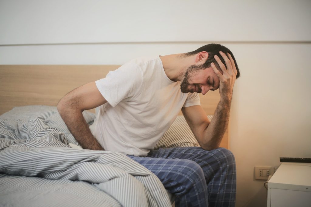 Jeune homme en pyjama souffrant de maux de tête le matin